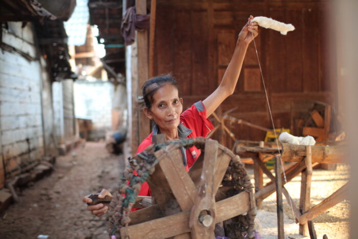 A woman working cotton with a spinning wheel. Our clothes are made by women working from home. Mothers who are continuing the heritage traditions of their ancestors. Hands who are slowly disappearing as it is estimated that 98% of women who make our clothes don’t earn a living wage. Regenerative farming.