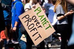 Degrowth in the Fashion Industry. Planet over profit protest sign.