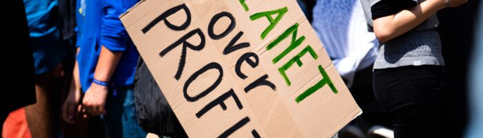 Degrowth in the Fashion Industry. Planet over profit protest sign.